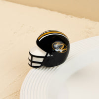 A small, decorative University of Missouri football helmet mini with a black and gold color scheme and the Missouri tiger logo on the side.