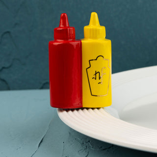 Red and yellow condiment bottle minis on a white plate with a blue background