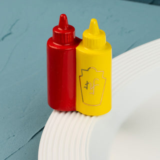 Red and yellow condiment bottle mini on a white surface with a blue background