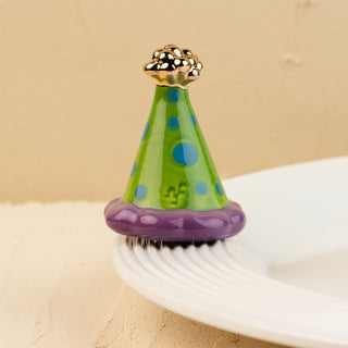 Colorful party hat mini with blue polka dots, and gold top on a beige background.