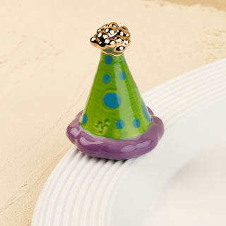 Colorful party hat mini with blue polka dots, and gold top on a beige background.