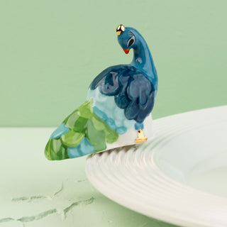 Decorative peacock figurine on a white base with a green background