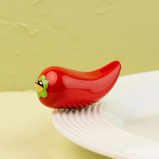 Red pepper mini with green stem on a white plate against a light green background