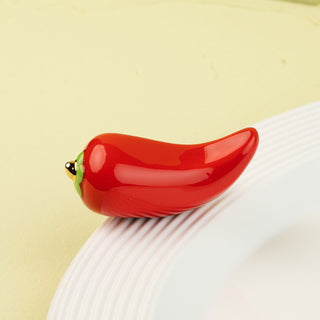 Red pepper mini with green stem on a white plate against a light green background
