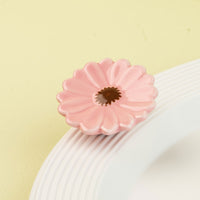 Pink flower mini on a white surface with a green background