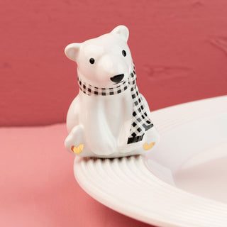 White polar bear mini with a black and white checkered scarf on a pink background