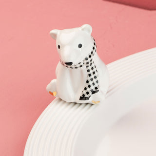 White polar bear mini with a black and white checkered scarf on a pink background