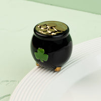 Black pot with a green clover mini on a white surface against a light green background