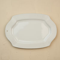 White ceramic platter with wavy edge on a beige background