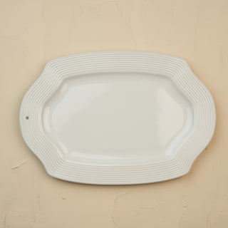 White ceramic platter with wavy edge on a beige background