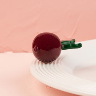 This image features a charming, decorative mini radish with a deep, rich red color and a contrasting green stem. Designed to add a playful yet garden-inspired touch to any setting, this radish mini.