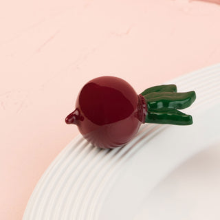 This image features a charming, decorative mini radish with a deep, rich red color and a contrasting green stem. Designed to add a playful yet garden-inspired touch to any setting, this radish mini.