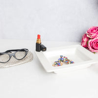 red lipstick and square napkin holder with pink roses and reading glasses