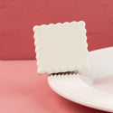 White square scalloped mini on a white plate with a red background