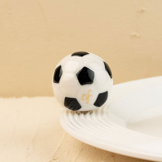 Black and white soccer ball mini t on a beige surface