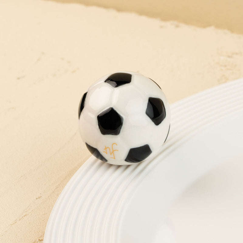 Black and white soccer ball mini t on a beige surface