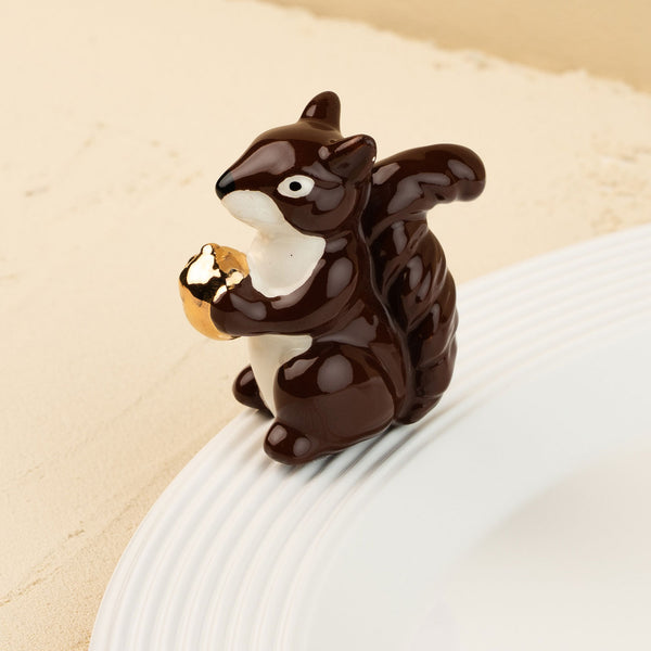 Squirrel mini holding a nut on a beige background