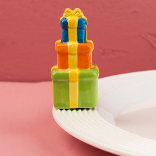Colorful gift box-shaped mini on a white plate with a pink background