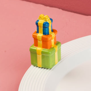 Colorful gift box-shaped mini on a white plate with a pink background