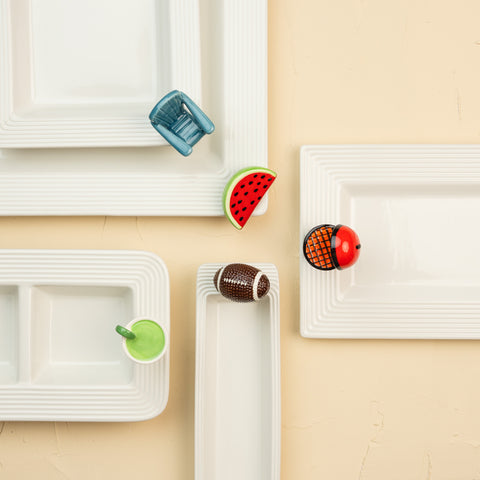 White rectangular plates with colorful fruit-shaped cutouts on a beige background