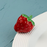 Red strawberry-shaped mini on a white plate against a blue background