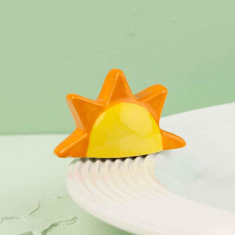 Sun-shaped mini with orange and yellow gradient on a white surface with a light green background