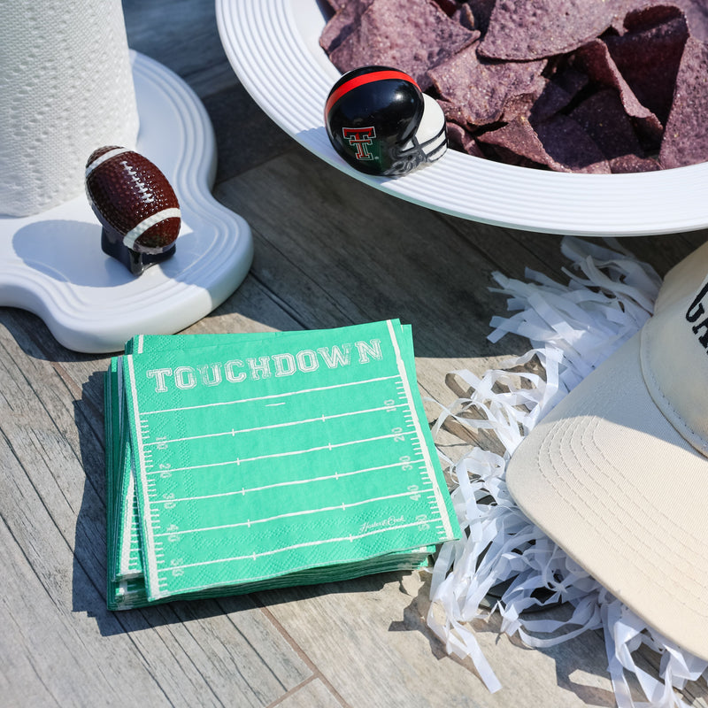 Gameday-themed items including a cap, football, and purple tortilla chips on a table.