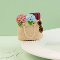 a tote bag mini filled with flowers, a book and sunglasses