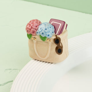 a tote bag mini filled with flowers, a book and sunglasses