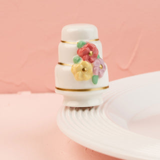 a white wedding cake mini with colorful flowers on a pink background