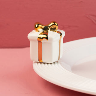 White ceramic gift box mini with gold bow on a pink background