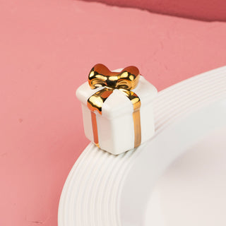 White ceramic gift box mini with gold bow on a pink background