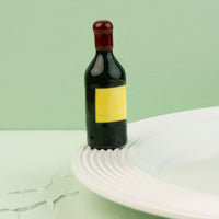 wine bottle mini with a yellow label on a white plate against a light green background