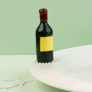 wine bottle mini with a yellow label on a white plate against a light green background