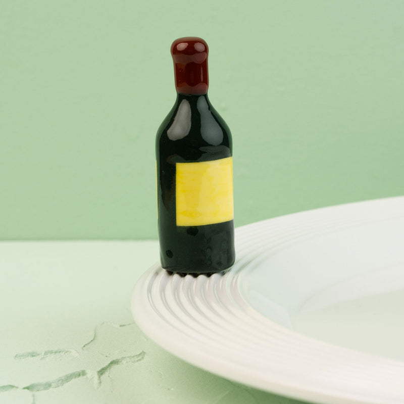 wine bottle mini with a yellow label on a white plate against a light green background