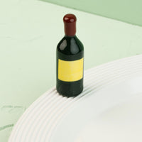 wine bottle mini with a yellow label on a white plate against a light green background