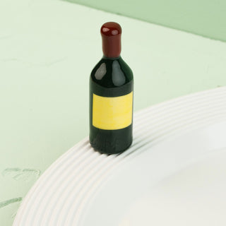 wine bottle mini with a yellow label on a white plate against a light green background