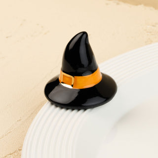 Black witch hat with an orange band on a white surface