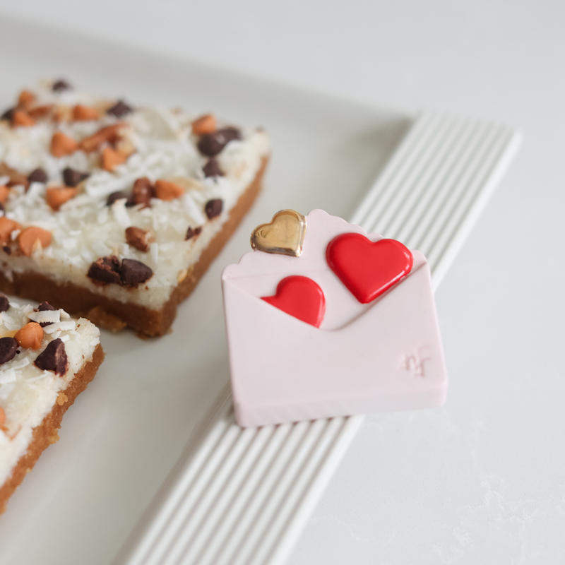 love notes mini with hearts coming out of an envelope on a melamine tray with brownies