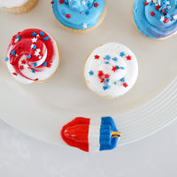 red, white, and blue popsicle  and patriotic cupcakes on a round pinstripes platter