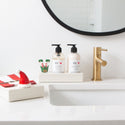 hand soap and lotion holder with elf mini and santa hat mini and napkin holder with santa napkins on a bathroom sink